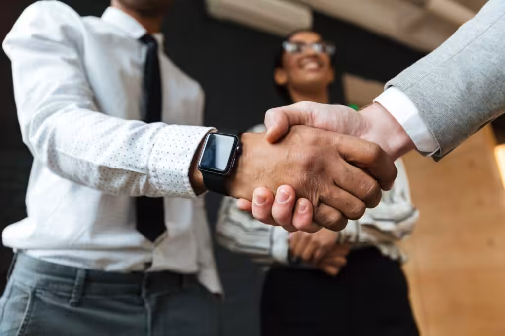 Handshake at business meeting with smiling colleagues.