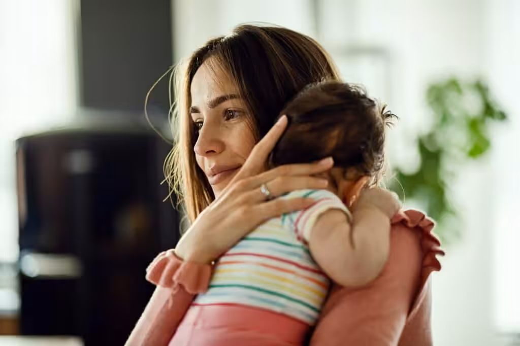 Mother embracing baby affectionately at home.