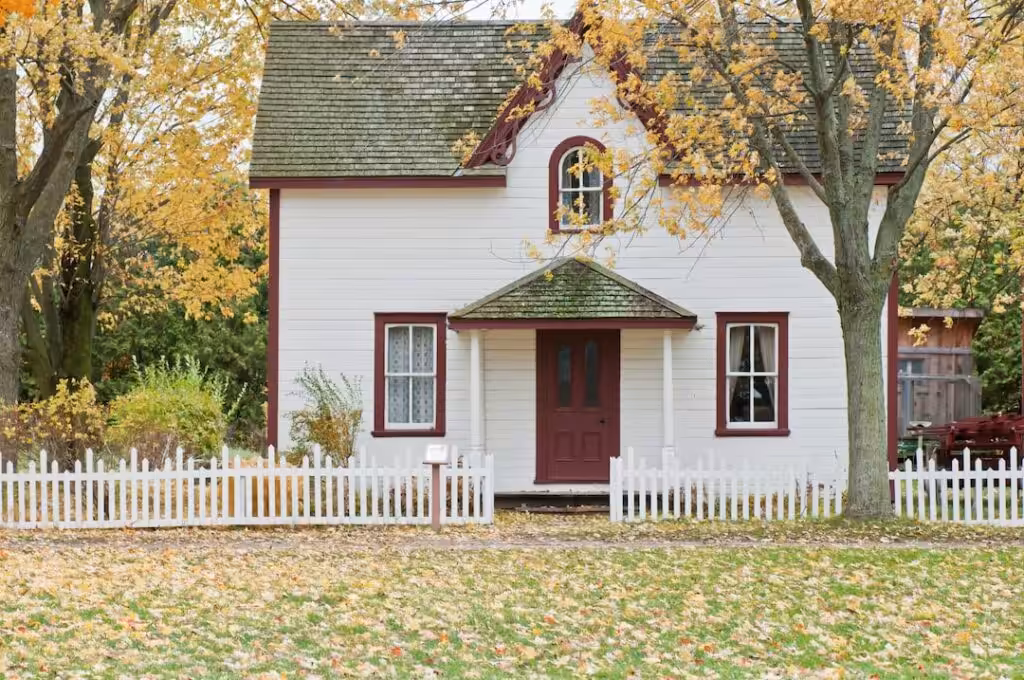 Charming white house with picket fence in autumn.